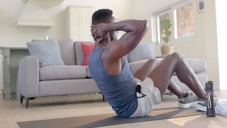 Focused-african-american-man-doing-crunches-in-sunny-living-room,-slow-motion