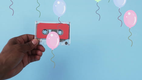 Animation-of-balloons-and-hand-holding-tape-on-blue-background