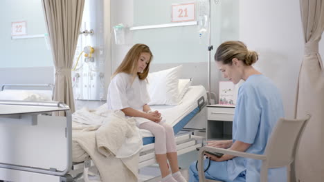 Caucasian-female-doctor-talking-with-girl-patient-sitting-on-hospital-bed,-slow-motion