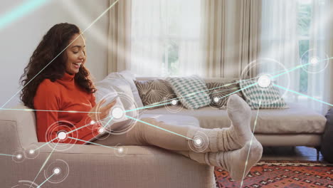 Animation-of-network-of-connected-circles-over-happy-biracial-woman-using-smartphone