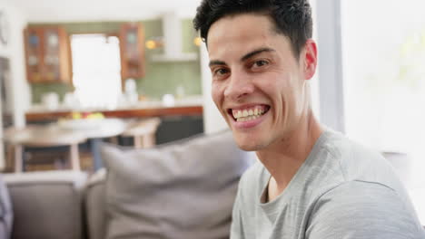 Portrait-of-happy-biracial-man-smiling-in-living-room-at-home,-copy-space,-slow-motion