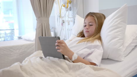Caucasian-girl-patient-lying-in-hospital-bed-using-tablet,-slow-motion