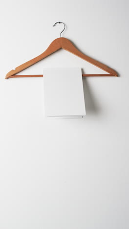 Vertical-video-of-book-on-hanger-with-white-blank-pages-and-copy-space-on-white-background