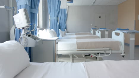 Row-of-empty,-freshly-made-beds-and-equipment-in-empty-hospital-ward,-copy-space,-slow-motion
