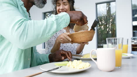 Feliz-Pareja-Birracial-Desayunando-Huevos-Revueltos-Y-Hablando-En-La-Cocina,-Cámara-Lenta