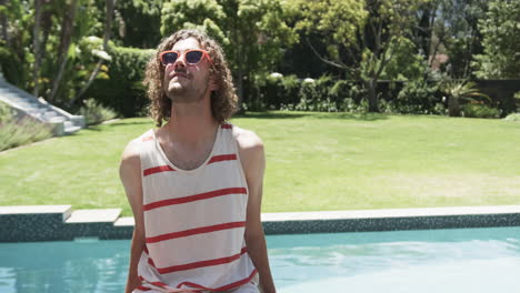 Young-Caucasian-man-enjoys-the-sun-by-the-pool,-with-copy-space