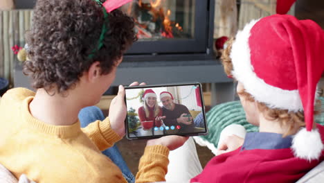 Happy-caucasian-couple-and-male-friends-having-christmas-tablet-video-call,-slow-motion