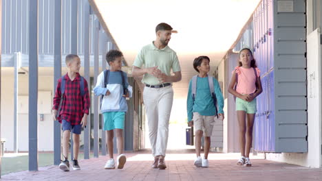 Young-Asian-man-walks-with-students-at-school
