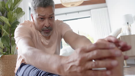 Focused-senior-biracial-man-practicing-yoga,-stretching-at-home,-slow-motion