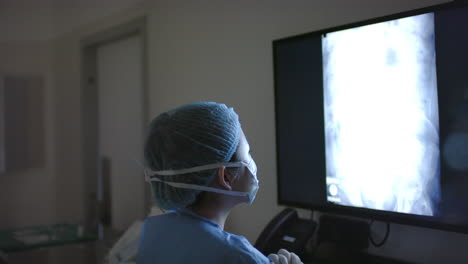 Asiatische-Chirurgin-Betrachtet-Röntgenaufnahmen-Im-Operationssaal,-Zeitlupe