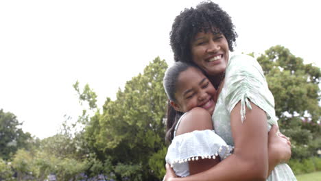 Happy-african-american-mother-and-daughter-hugging-in-garden,-copy-space,-slow-motion