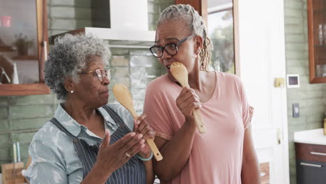 Glückliche-ältere-Afroamerikanische-Freundinnen-Bereiten-Essen-Zu,-Singen-In-Der-Küche,-Zeitlupe