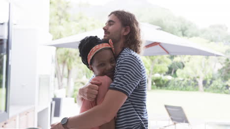 Diverse-couple,-a-young-African-American-woman-and-Caucasian-man-are-hugging-at-home