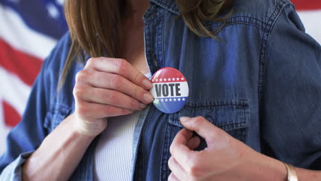 Middle-aged-Caucasian-woman-pins-a-'VOTE'-badge-on-her-shirt,-with-copy-space