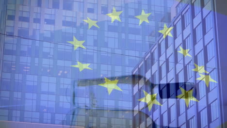 Animation-of-flag-of-eu-and-spinning-bottle-over-modern-office-buildings