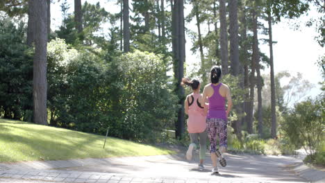 Asian-female-friends-running-near-forest-on-sunny-day,-slow-motion