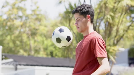 Hombre-Birracial-Feliz-Practicando-Habilidades-Futbolísticas-En-Un-Jardín-Soleado,-Espacio-Para-Copiar,-Cámara-Lenta