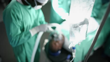 African-american-male-surgeon-using-anaesthetic-mask-on-patient-in-operating-theatre,-slow-motion