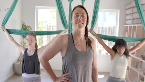Happy-diverse-fitness-teenage-girls-exercising-in-aerial-yoga-class-with-female-coach,-slow-motion