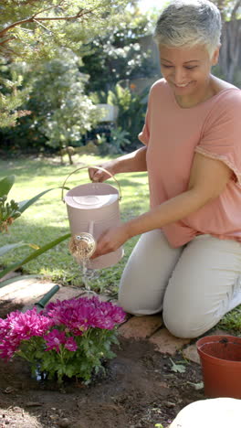 Vídeo-Vertical-De-Retrato-De-Una-Feliz-Mujer-Birracial-Mayor-Trabajando-En-El-Jardín,-Cámara-Lenta