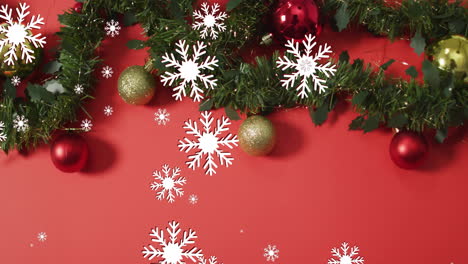 Animation-of-snow-falling-over-christmas-decorations-on-red-background