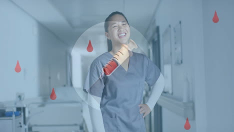 Animation-of-blood-drops-and-syringe-over-asian-female-doctor-in-hospital