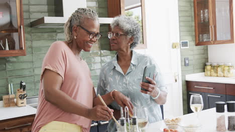 Glückliche-ältere-Afroamerikanische-Freundinnen,-Die-Salat-Mit-Smartphone,-Kopierraum-Und-Zeitlupe-Zubereiten