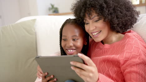 Happy-african-american-mother-with-daughter-using-tablet-at-home,-slow-motion