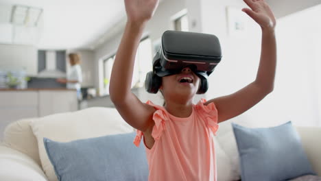 Happy-biracial-girl-wearing-vr-headset-using-virtual-interface-at-home,-copy-space,-slow-motion
