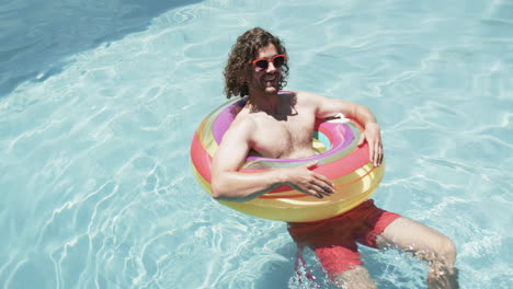 Young-Caucasian-man-enjoys-a-sunny-day-in-the-pool,-with-copy-space