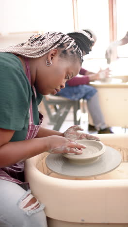 Focused-african-american-female-potter-using-potter's-wheel-in-pottery-studio,-slow-motion