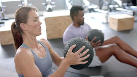 Fit-young-Caucasian-woman-and-African-American-man-exercising-at-the-gym-with-medicine-balls