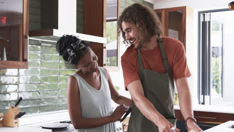 Diverse-couple,-a-young-African-American-woman-and-Caucasian-man,-cooking-together-at-home