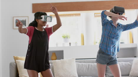 Happy-diverse-teenage-female-friends-playing-and-wearing-vr-headsets-at-home,-slow-motion