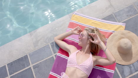 Young-Caucasian-woman-enjoys-the-sun-by-the-pool