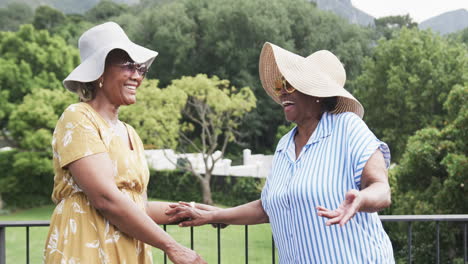 Portrait-of-happy-senior-african-american-female-friends-outside-in-sunglasses-and-hats,-slow-motion