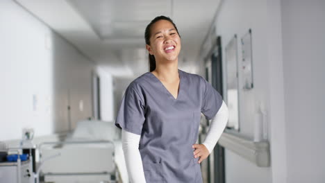 Portrait-of-happy-asian-female-doctor-wearing-scrubs-in-hospital,-slow-motion