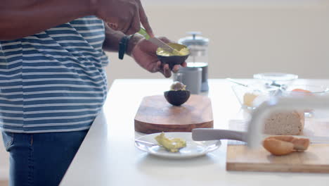 African-american-man-chopping-avocado-in-sunny-kitchen,-slow-motion