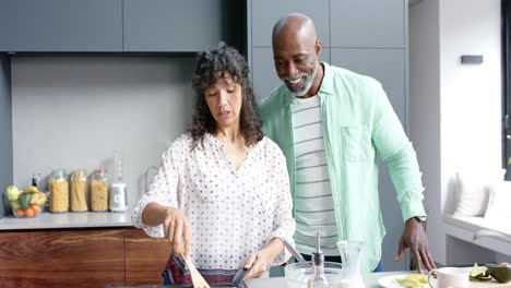 Happy-biracial-couple-preparing-eggs-for-breakfast-in-kitchen,-slow-motion