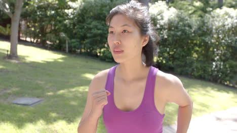 Happy-asian-woman-in-sportswear-running-in-garden-on-sunny-day,-slow-motion