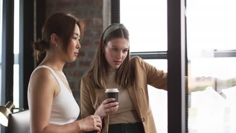 Asian-businesswoman-and-young-Caucasian-woman-discuss-over-laptop-in-an-office