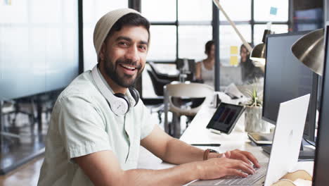 Young-man-with-beard-working-on-a-computer-in-a-modern-office-setting-for-his-business