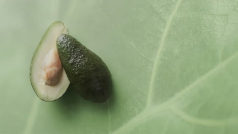 Composition-of-halved-avocado-over-green-leaf-background