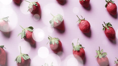 Composition-of-spots-of-light-over-strawberries-on-pink-background