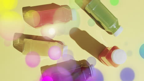 Composition-of-spots-of-light-over-bottles-with-fruit-juices-on-yellow-background