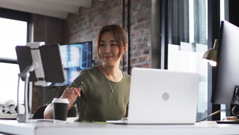 Asiatische-Geschäftsfrau-In-Einem-Modernen-Büro-Gibt-Einen-Daumen-Hoch,-Mit-Laptops-Und-Monitoren-Um-Sie-Herum