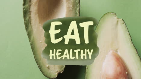 Animation-Eines-„Eat-Healthy“-Textes-über-Halbierter-Avocado-Auf-Grünem-Hintergrund