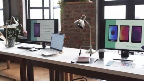 Modern-business-workspace-is-equipped-with-multiple-monitors,-a-laptop,-and-various-office-supplies