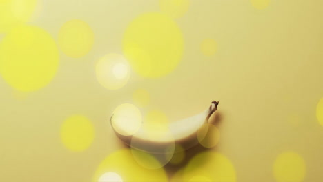 Composition-of-spots-of-light-over-banana-on-yellow-background