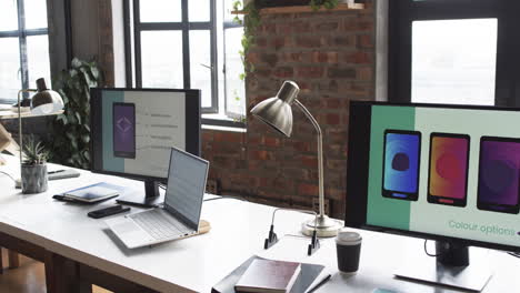 Modern-business-workspace-is-equipped-with-a-laptop,-two-monitors,-and-various-office-supplies